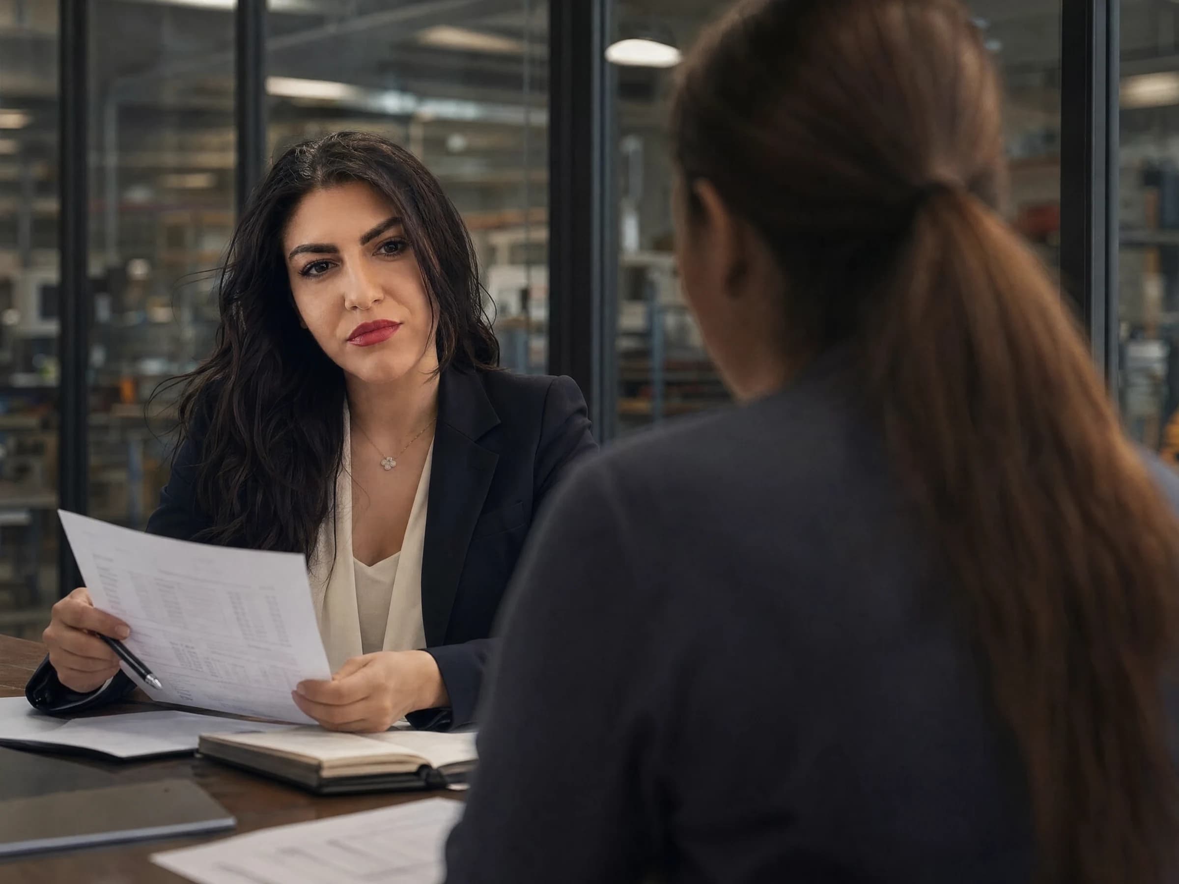 Small business consulting — an owner and an adviser reviewing a printed P&L at a workshop office desk, Canada