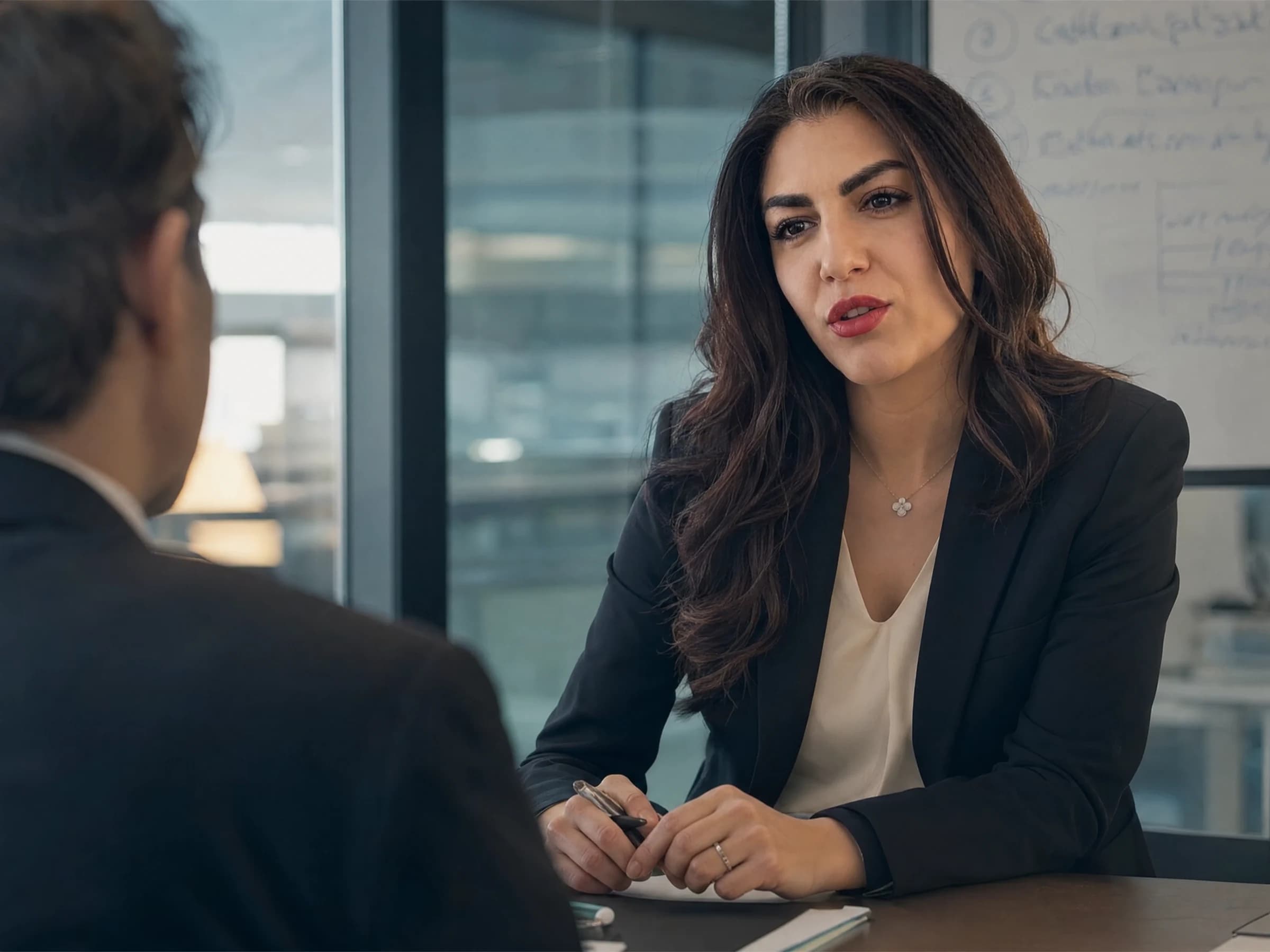 Leadership coaching — a manager mid-discussion in a glass-walled meeting room with a decision list on the whiteboard, Canada